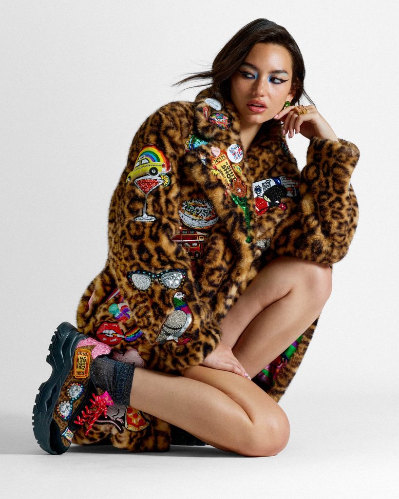 Model wearing an embellished leopard-print coat and trainers from the Kurt Geiger x Kelsey Randall 2026 collection.