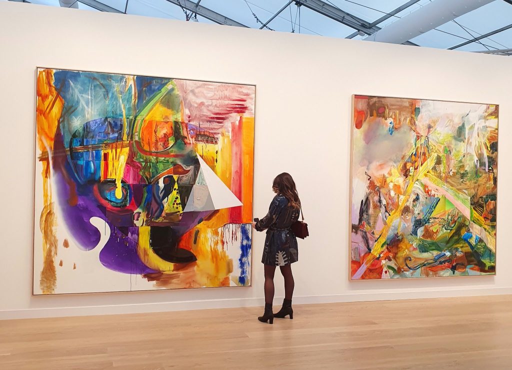A visitor stands between two large, colourful abstract paintings by Albert Oehlen at Gagosian’s Frieze London stand.