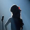 Amy Winehouse silhouette on stage under dramatic lighting with her signature beehive hairstyle