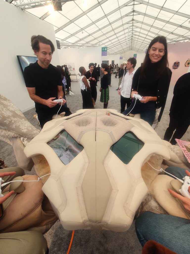 Players hold wired controllers around the screens embedded in Theo Triantafyllidis’s spider sculpture. Photography: Sharon Ayiglo.