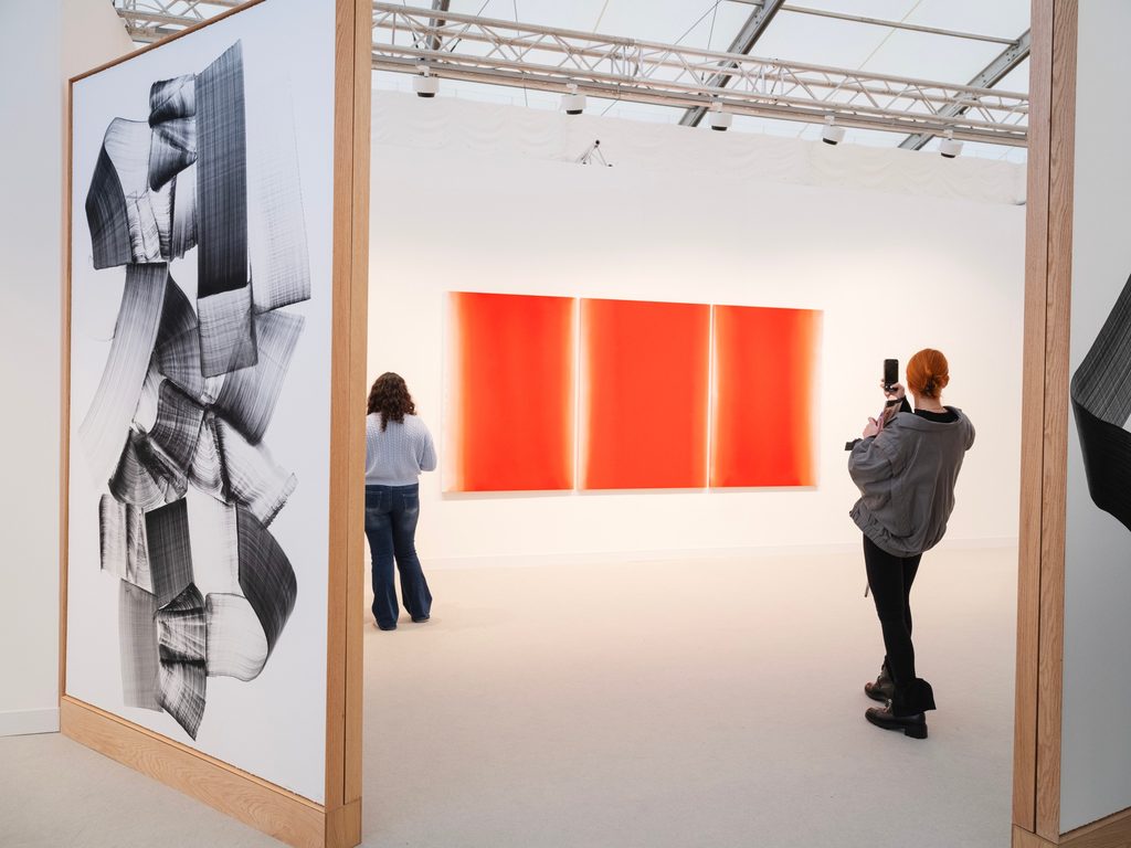 Visitors viewing abstract contemporary artworks at Johyun Gallery's stand during Frieze London 2025, including a vibrant orange triptych.