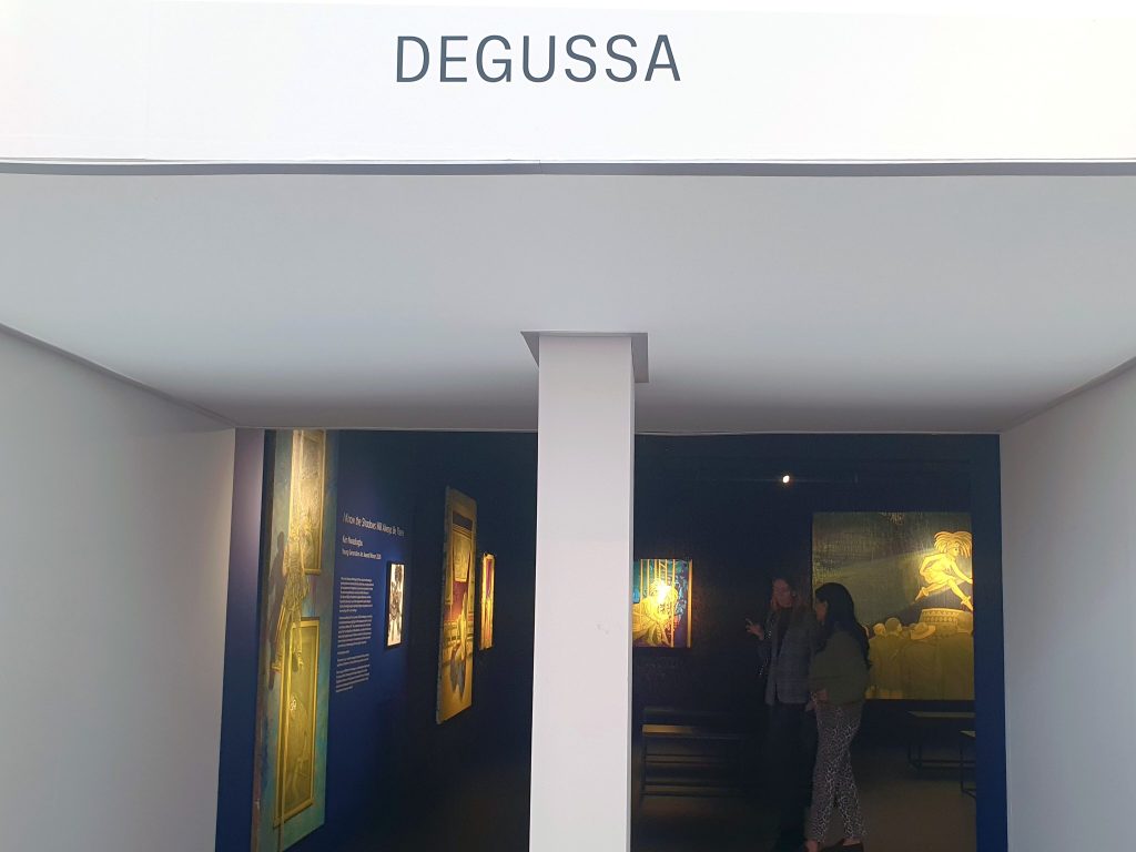 Entrance to the Degussa Lounge, with visitors and Ken Nwadiogbu’s yellow figures visible inside.