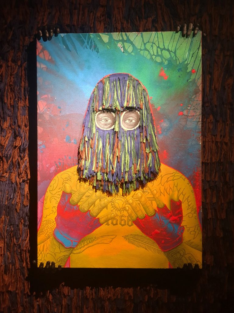 Ken Nwadiogbu painting of a yellow figure wearing a fringed mask, held at its edges by sculpted hands.