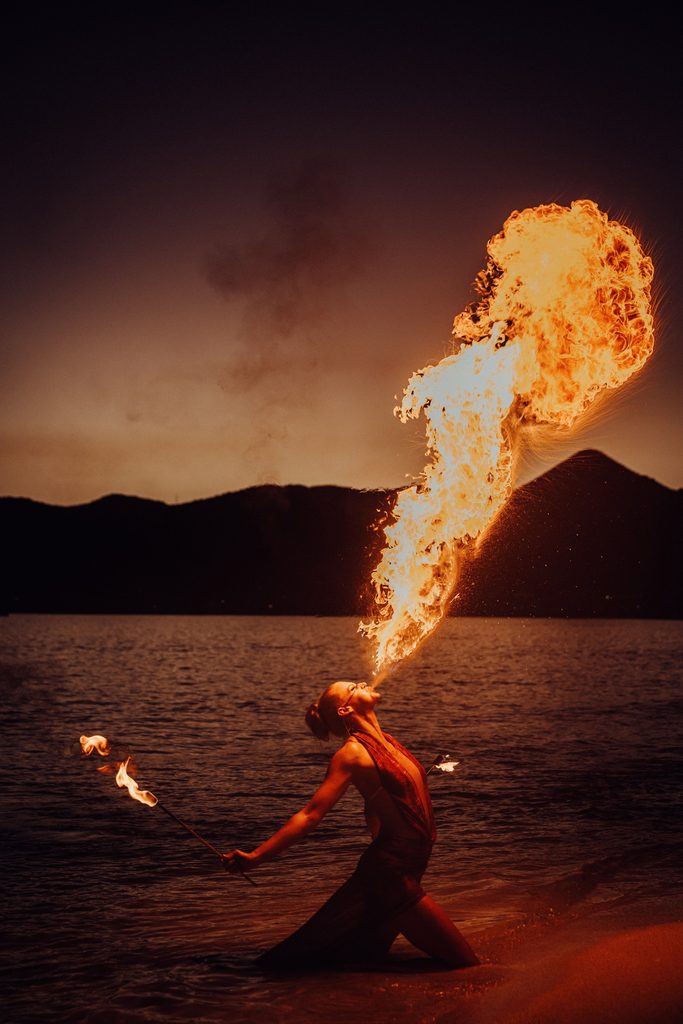 Fire performer creating a dramatic plume of flames beside the sea at SXM Festival 2026 in St. Martin