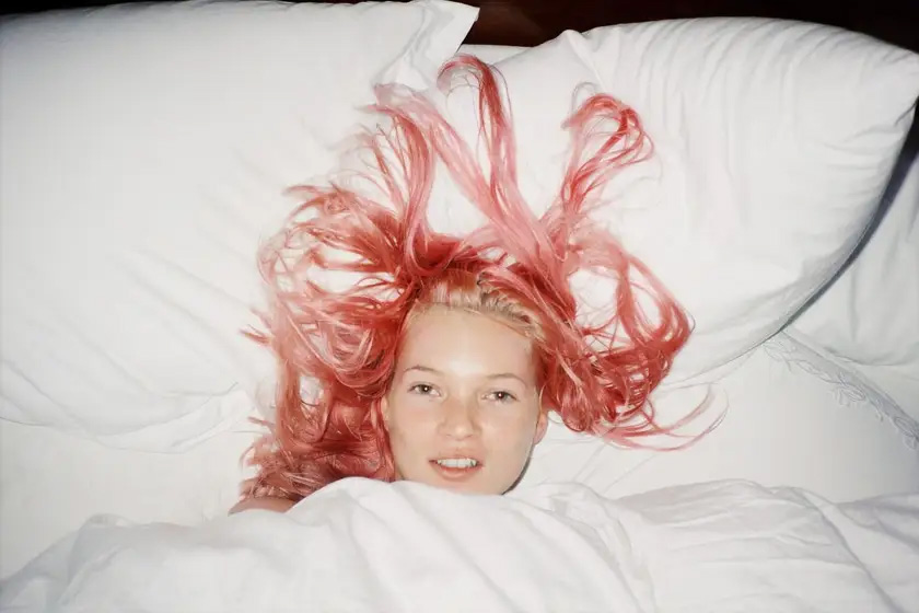 Kate Moss lying in bed with pink hair in Juergen Teller's 1998 photograph, featured in Tate Britain's The 90s: Art and Fashion exhibition.