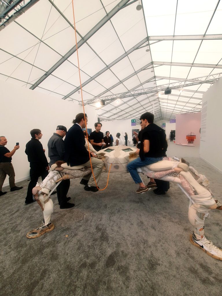 Visitors play on Theo Triantafyllidis’s pale textile-covered spider sculpture, with trainers at the ends of its legs.