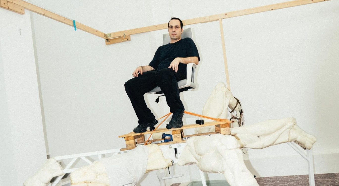Artist Theo Triantafyllidis seated on his large spider-like Feral Metaverse sculpture inside his Athens studio.