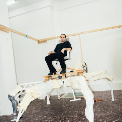 Artist Theo Triantafyllidis seated on his large spider-like Feral Metaverse sculpture inside his Athens studio.