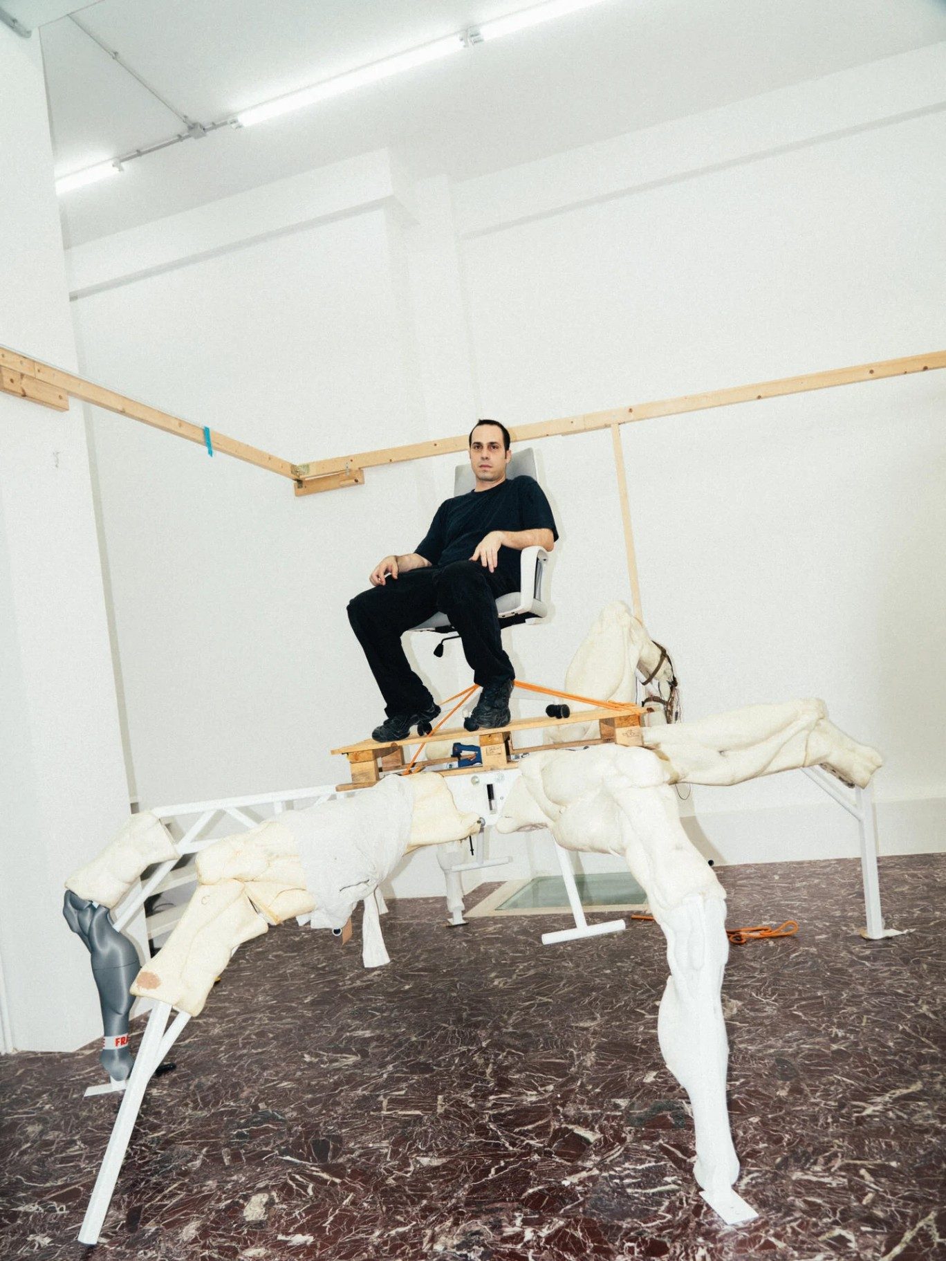 Artist Theo Triantafyllidis seated on his large spider-like Feral Metaverse sculpture inside his Athens studio.